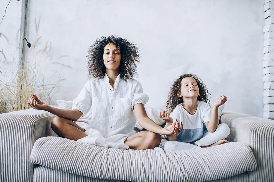 Employee Benefits - Mother and Daughter Meditating on Couch