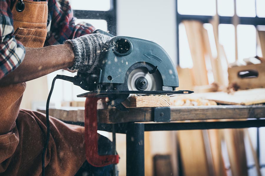 Specialized Business Insurance - Closeup of Contractor Using Circular Saw in Workshop