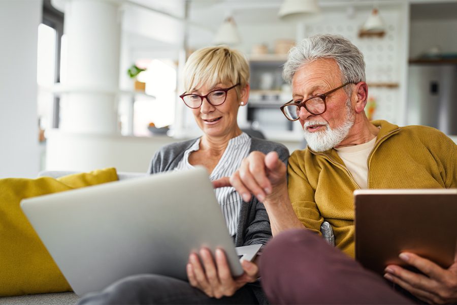 Medicare - Senior Couple Smiling While Working on a Laptop at Home